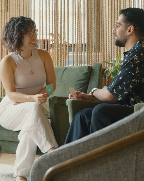 Two guests trading question cards on a couch at a BeHeld gathering