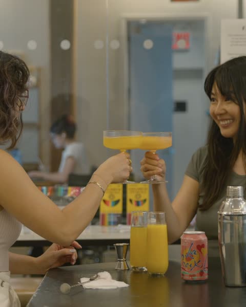Two returning guests toasting the drinks they mixed for each other
